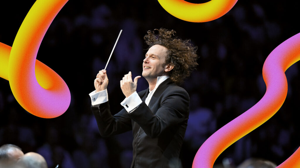 A man with curly hair holds a conductor's baton in his right hand. His hair and the baton are up in the air. Around the man are yellow and pink streaks (the BBC Proms 2024 branding)